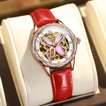 Watch with red strap and butterfly design on a white cushion